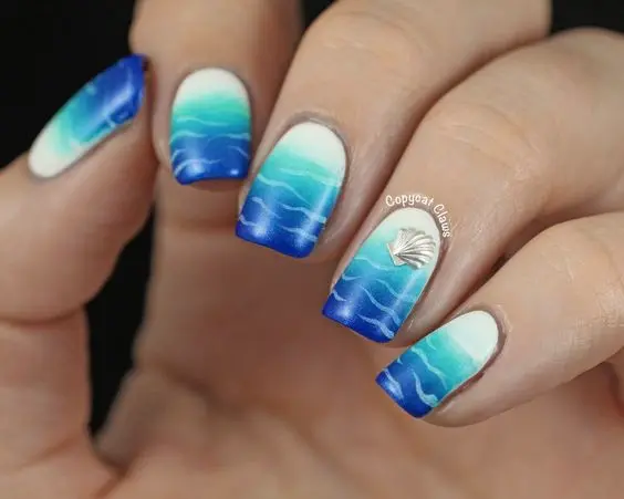 These square-shaped nails feature a serene ocean wave design in gradient blues, symbolizing a calm summer day at the beach. The soft blue tones create a refreshing look, ideal for summer vibes.