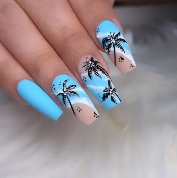 Ballerina-shaped nails with blue skies, sandy beaches, and black palm trees. The contrast of blue and beige captures the perfect summer beach sunset.