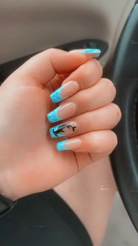 Ballerina-shaped nails with light blue marble French tips and a dolphin accent nail. The simple yet elegant design is perfect for a summer beach look.