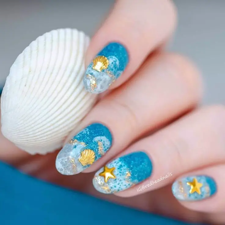 Short, rounded-shaped nails with a blue and white gradient, adorned with golden seashells and starfish. This design captures the luxury and charm of a summer beach.