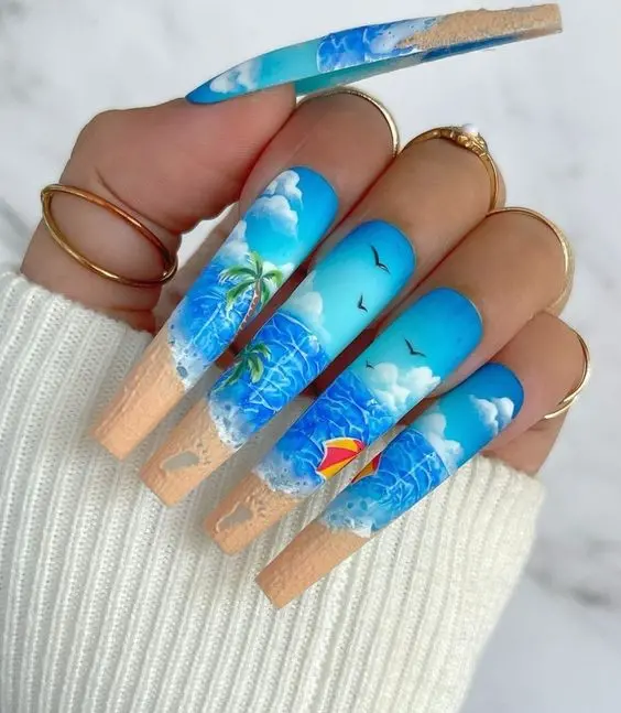 Extra-long nails with detailed beach scenes, palm trees, and ocean waves in bright blue and sandy colors. Perfect for an adventurous summer look.