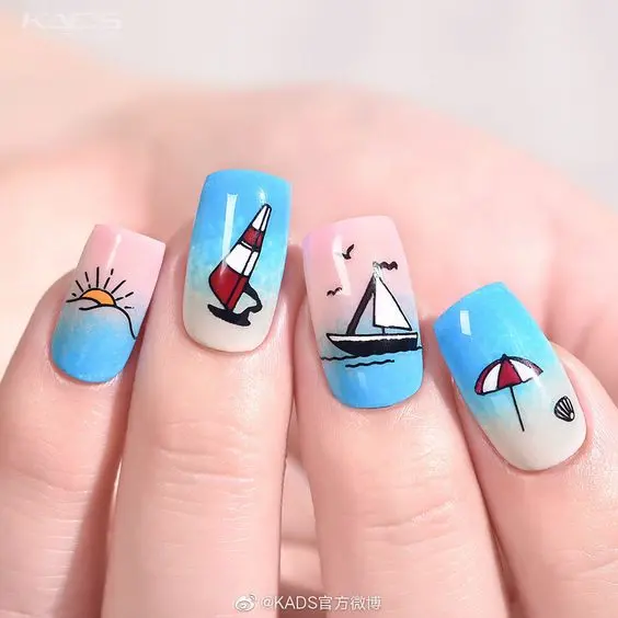 Squoval-shaped nails with vibrant blue and pink ombre backgrounds, decorated with sailboats, sun, and beach umbrellas, ideal for a fun summer day by the sea.