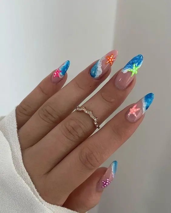 This vibrant design on stiletto nails showcases blue ocean waves and colorful starfish. The playful mix of blue hues and bright starfish accents highlights a fun and energetic summer beach theme.