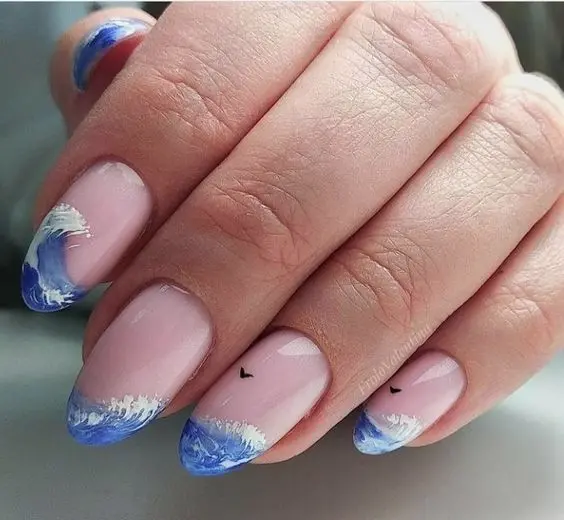 Short, almond nails with clear base and blue wave tips, featuring tiny bird details, convey the tranquility of a summer beach scene.