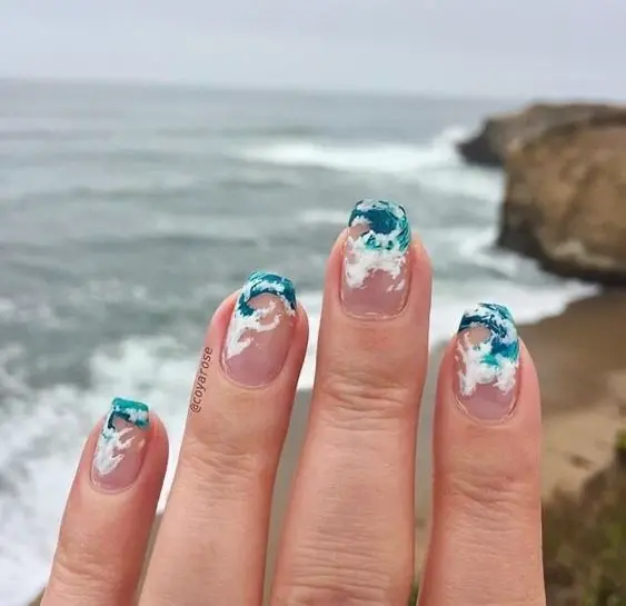 Short nails with clear bases and blue wave tips. This minimalist design is perfect for a subtle yet elegant summer beach look.