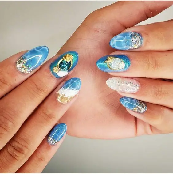 Almond-shaped nails featuring blue water effects, glittery seashells, and beach-themed designs, reflect a playful and sparkling summer day.