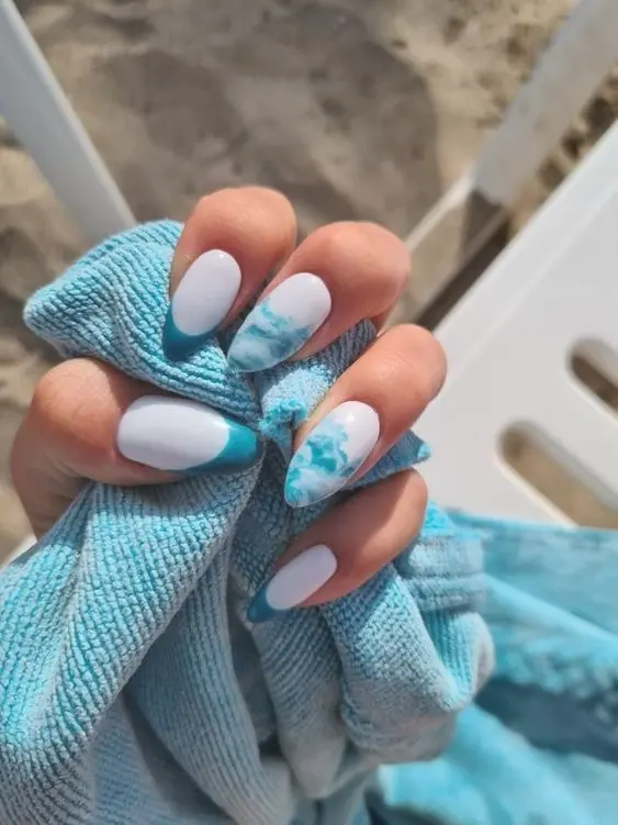 These stiletto nails depict a beautiful beach with blue waves. The combination of blue and gold brings out the summer beach aesthetic, perfect for vacation vibes.