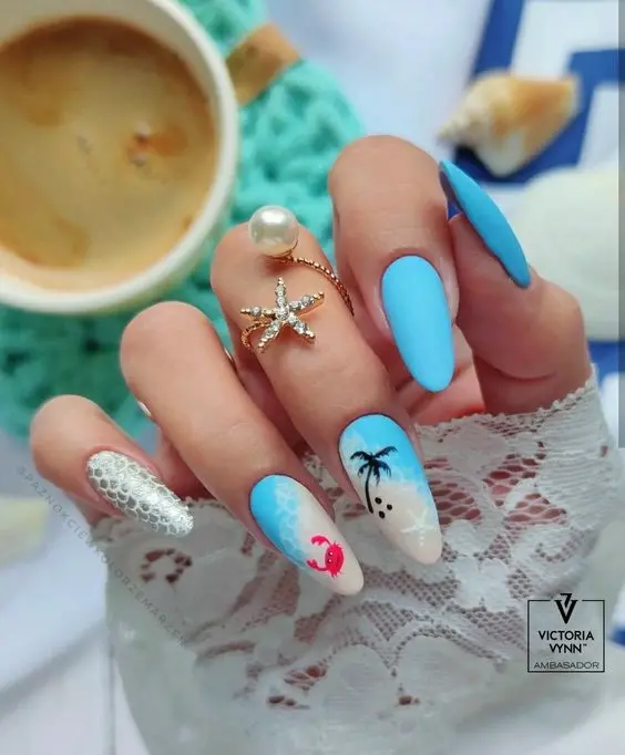 These nails feature a almond shape with a beach theme. The design includes a mix of vibrant blue shades, white accents, and detailed beach elements like palm trees and a crab. The bright colors and intricate designs evoke a fun and relaxing summer vibe.