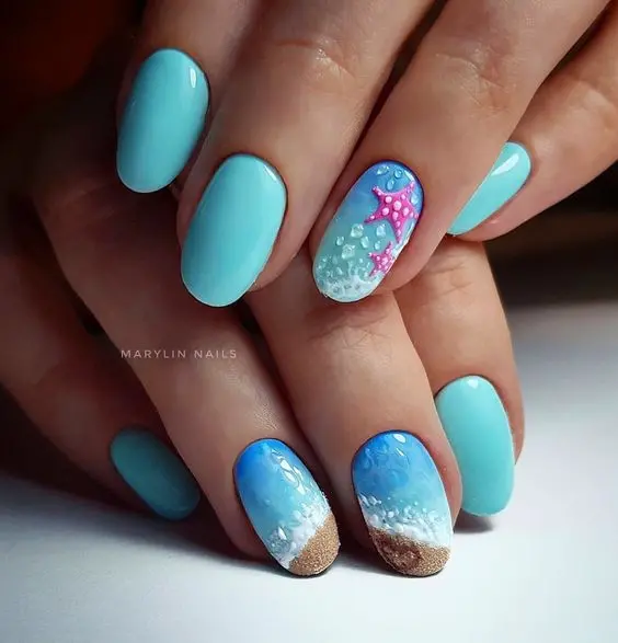 Oval-shaped nails with a gradient of blue to sandy beige, adorned with starfish and sea foam. The detailed design evokes a relaxing day at the beach, perfect for summer.