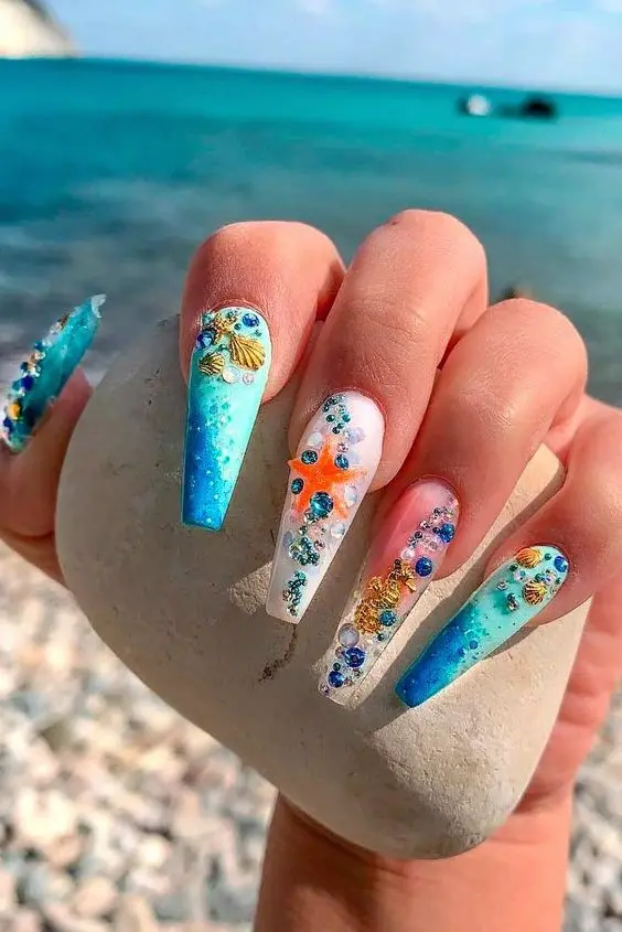 Long ballerina-shaped nails with blue and white gradients, adorned with 3D starfish and seashells. This vibrant design captures the essence of an underwater summer adventure.