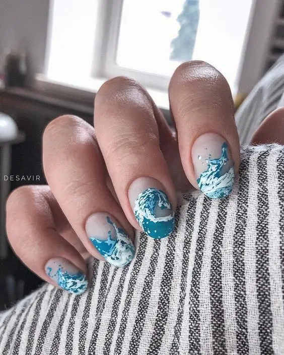 Oval nails with a beach scene design, showcasing vivid blue and sandy gradients. Adorned with seashell and starfish embellishments, these nails evoke the tranquility and charm of a summer seaside.