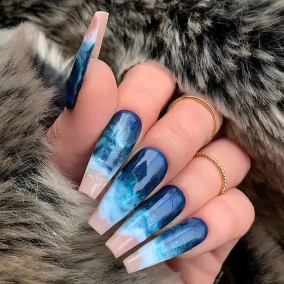 Long ballerina-shaped nails with dark blue and white cosmic wave patterns. The mystical and deep colors reflect the mysterious allure of the ocean, ideal for a stylish summer look.