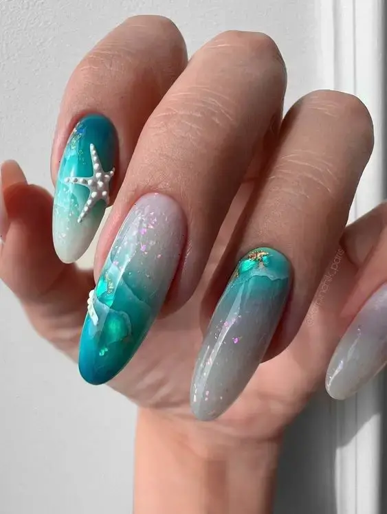 Almond-shaped nails with gradient blue and white, decorated with starfish and sea-inspired patterns, embody the vibrant energy of summer by the sea.