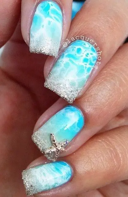 Square-shaped nails with blue and white wave designs, topped with glitter and a starfish. This sparkling design brings the beauty of the beach to your summer style.