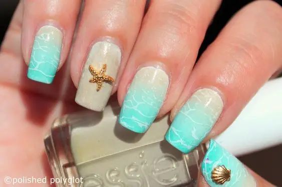 Medium square-shaped nails with a sandy gradient, featuring starfish and seashell accents. The soft, pastel colors evoke a serene summer beach experience.