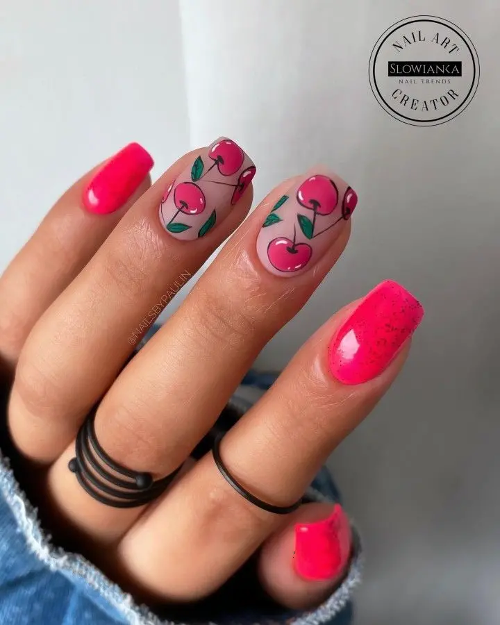 A unique summer nail art, squoval short nails painted hot pink, adorned with stylized cherry illustrations, perfect for a fun seasonal look.