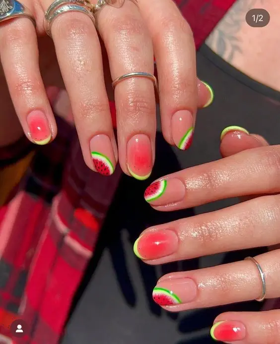 Short, natural-shaped nails feature a refreshing watermelon design with green borders, blending into a warm, sunset-inspired gradient.