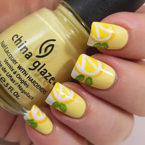 Sunny yellow nails with a glossy finish, adorned with lemon slice art and green leaf accents, invoke the zesty spirit of summer.