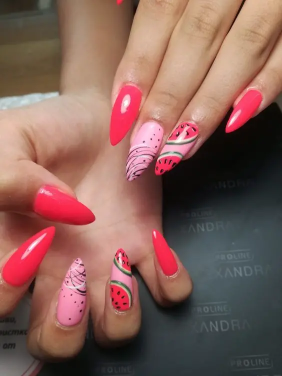 A bright and playful manicure with neon pink stiletto nails, featuring watermelon design on select nails, screams summer fun.