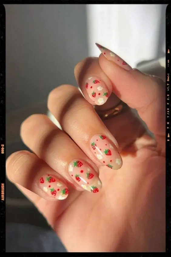 Translucent nails sprinkled with red and green strawberry accents capture the essence of summer with a light and airy touch, ideal for sunny days.