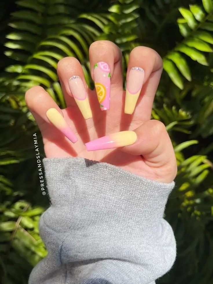 A playful array of summer fruits on a gradient of yellow and pink nails, finished with a touch of citrus charm, makes for an irresistibly fresh manicure.