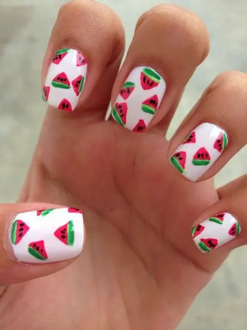 Crisp white squoval-shaped nails, sprinkled with tiny watermelon slices, channel a light-hearted summer picnic vibe.