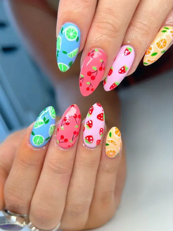 A playful mix of fruity designs on almond nails, featuring vibrant strawberries, limes, and oranges against pastel backgrounds for a juicy summer vibe.