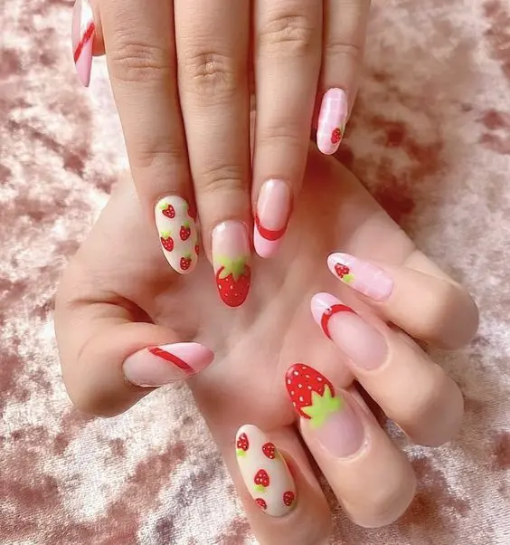 A delightful blend of strawberry designs set against a pale pink and red backdrop, these nails combine candy stripe details for a whimsical summer treat.