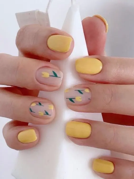 This design combines pastel yellow nails with floral accents on clear bases. The short, squoval shape and delicate yellow tulips create a subtle yet stylish look, ideal for a refreshing summer manicure.