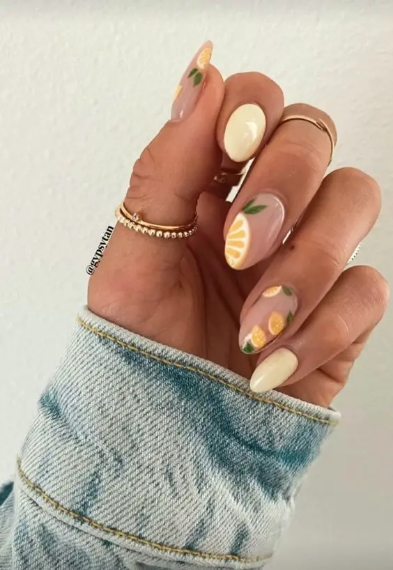 This design combines almond-shaped nails with clear bases and yellow fruit accents. The nails feature citrus slice designs and solid yellow, creating a vibrant and refreshing look perfect for a lively summer vibe.