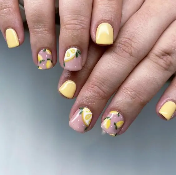 This design showcases short, square nails with lemon motifs on a light pink background. The bright yellow polish and citrus elements reflect a refreshing and zesty summer feel, making it perfect for sunny days.