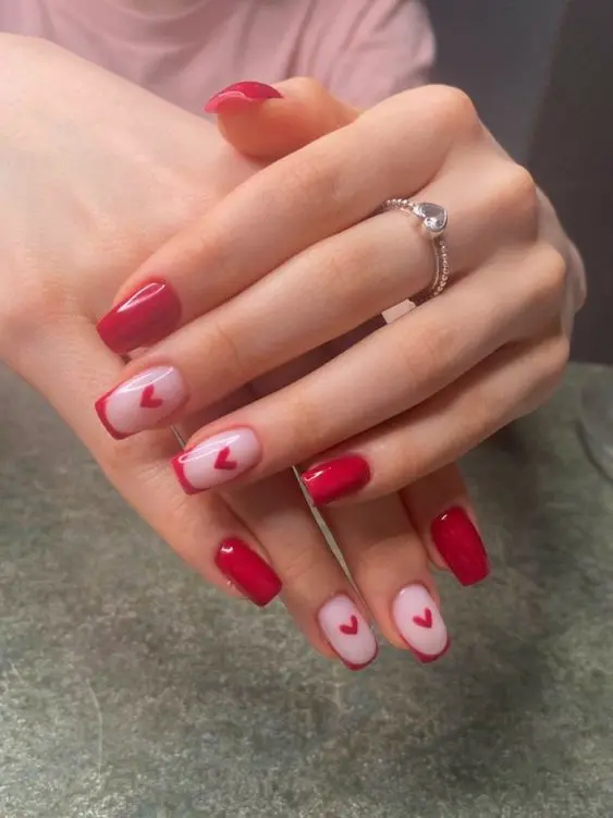 This nail design combines classic red polish with delicate heart accents. The pink base with red heart details adds a touch of sweetness and romance, making it an ideal choice for a subtle yet charming Valentine\'s Day manicure.