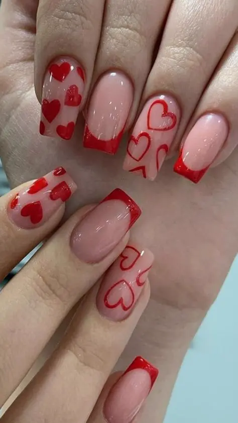 The nails in this image feature a chic and contemporary design with a mix of red polish and clear nude bases adorned with red heart outlines. The medium square shape enhances the modern aesthetic, perfect for trendy and fashionable looks.