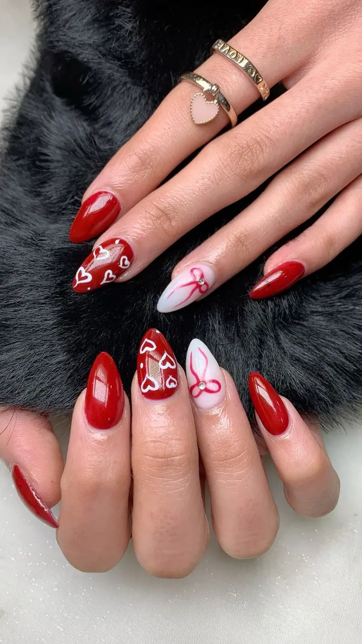 Standing out with a blend of glossy red and nude pink, this nail design is adorned with hearts and bows. The stiletto shape adds drama, making it a striking look for those who want to stand out.