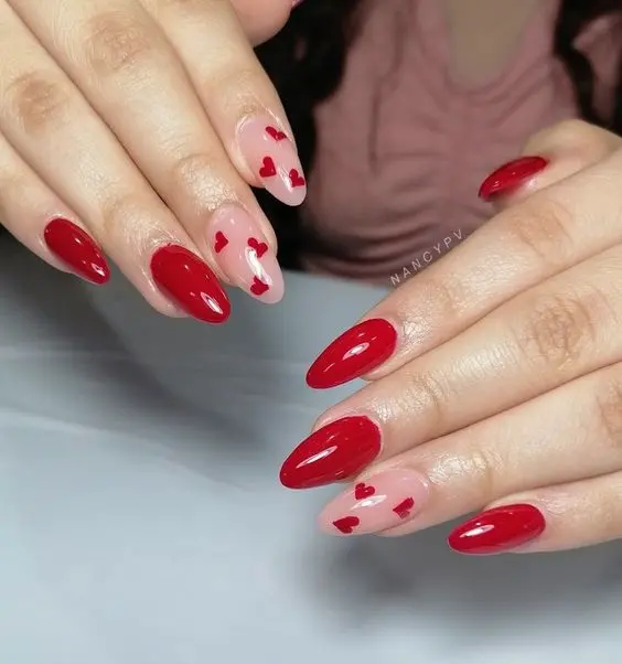 These bold almond-shaped nails combine vibrant red polish with nude accent nails decorated with red hearts. The striking red color and cute heart details make this design perfect for a confident and romantic style.