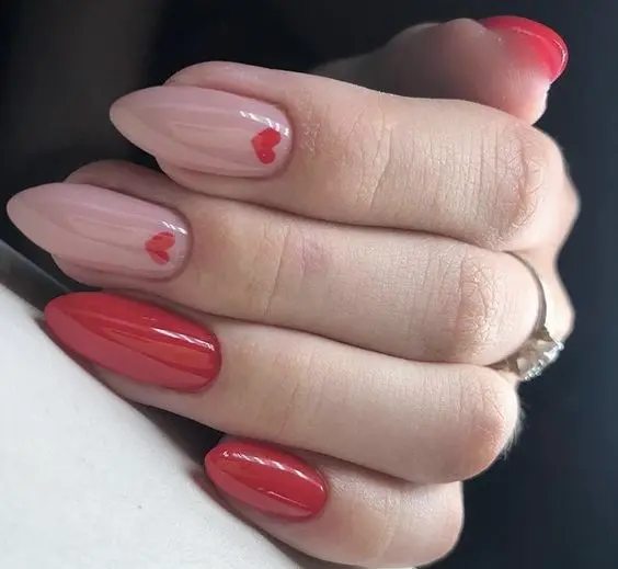 This design combines pink and deep red shades on stiletto nails, with a minimalistic heart outline on the red nail. The sleek, elongated shape emphasizes elegance and romance.