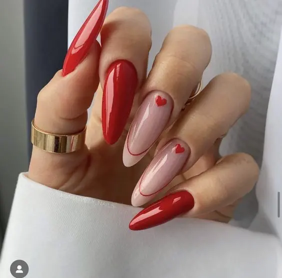 These stylish almond-shaped nails feature a combination of glossy red polish and nude nails with red heart accents. The mix of bold red and delicate heart details creates a chic and sophisticated look perfect for any occasion.