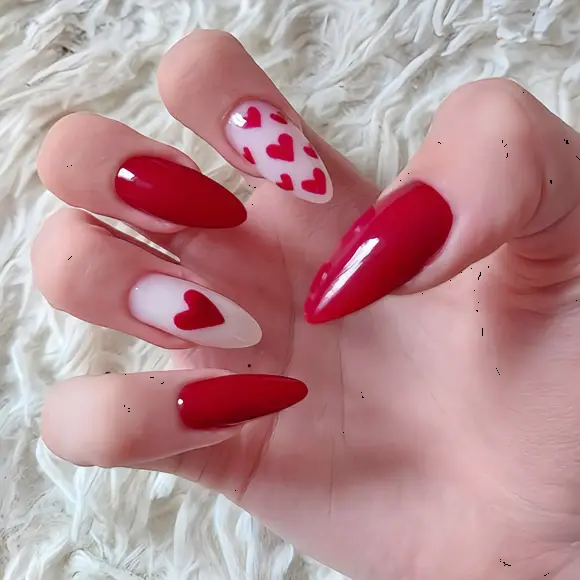 These red heart nails feature a striking combination of bold red polish and delicate heart designs on an almond-shaped form. The red hearts on the accent nails add a playful and romantic touch, perfect for expressing love and affection.