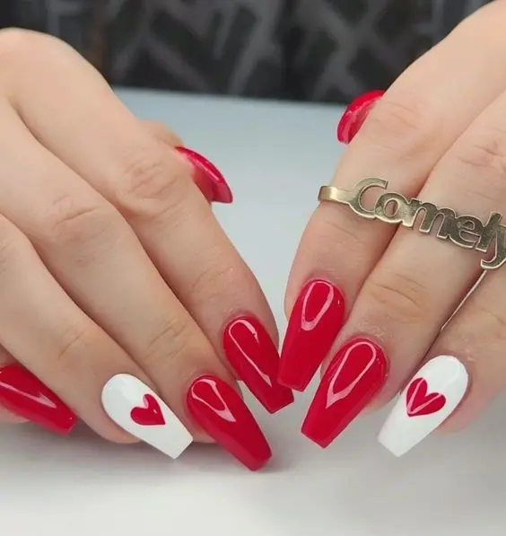 These eye-catching ballerina-shaped nails combine glossy red polish with white accent nails featuring red heart designs. The bold colors and simple heart details create a striking and romantic look.