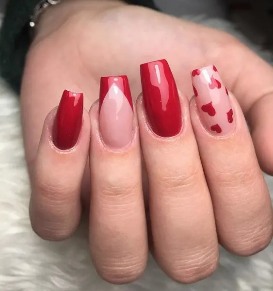 These stylish ballerina-shaped nails feature a mix of glossy red polish and nude accents with red heart designs. The bold red color and romantic heart patterns create a chic and modern look.