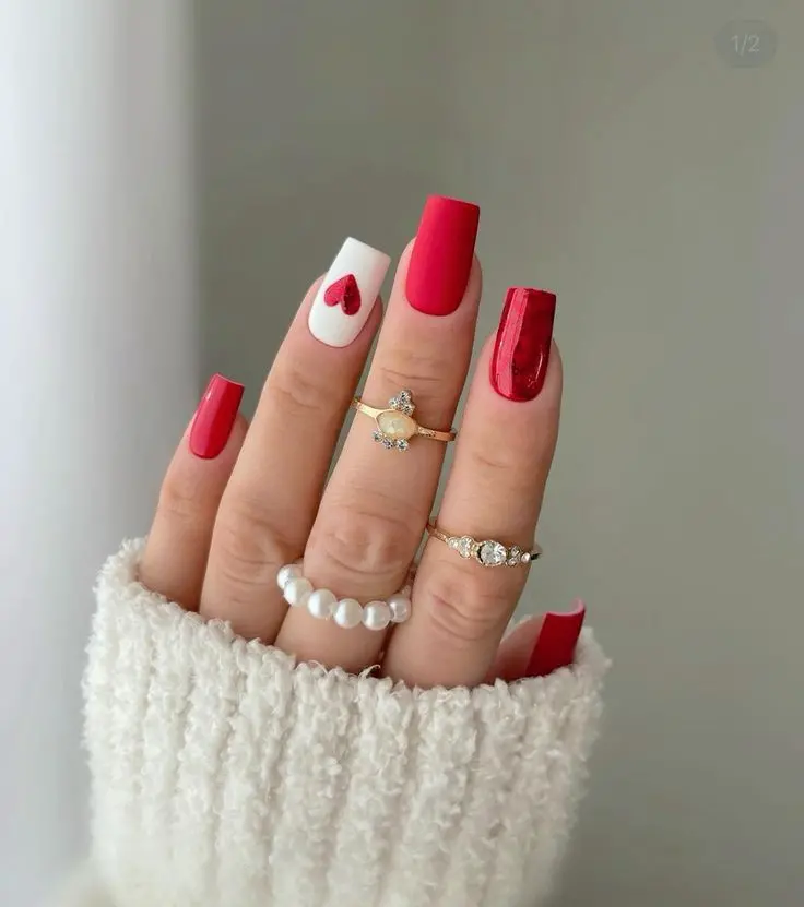 A mix of solid red nails and accent nails featuring white with red hearts, this design is both bold and romantic. The shiny finish and heart details make it perfect for celebrating love or adding a playful touch to any outfit.