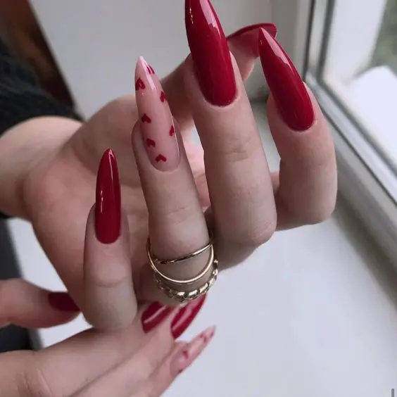 These long, red stiletto nails are combined with nude accents adorned with tiny red hearts. The glossy finish enhances the bold red color, making this design perfect for those who want a dramatic and romantic style, ideal for special occasions or a night out.