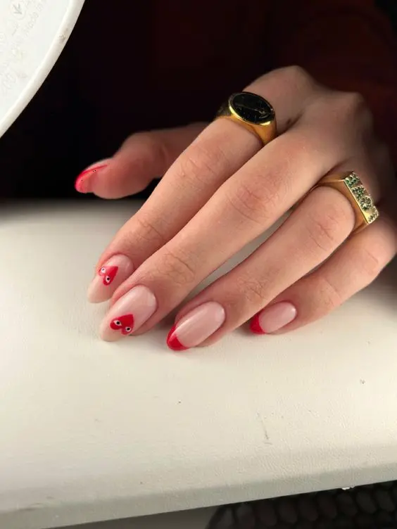 These elegant red heart nails are subtly stylish, with red tips and small heart accents on a natural base. The almond shape enhances the feminine and romantic feel, perfect for any occasion.