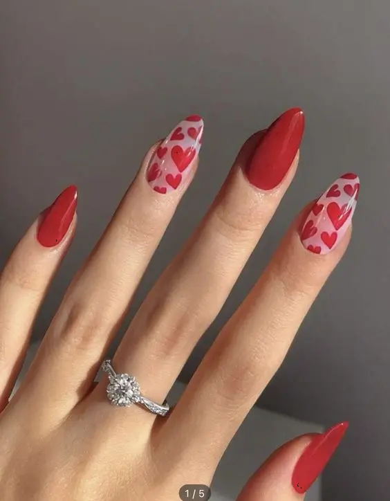 These vibrant red nails feature two accent nails with heart patterns on a nude base. The almond-shaped nails and combination of bold red and playful hearts create a fun and lively design, perfect for expressing love and joy.