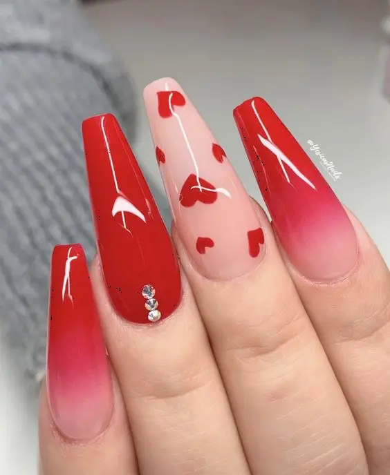 These elegant ballerina-shaped nails showcase a red ombre effect with a nude base, adorned with red heart designs and a single rhinestone. The gradient and heart accents offer a sophisticated and romantic touch.