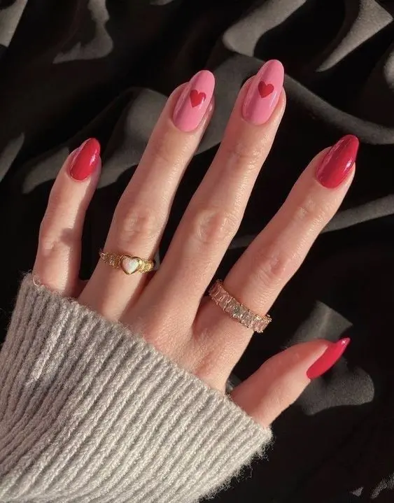 These classic red and pink heart nails are perfect for a romantic look. The almond-shaped nails are painted in shades of red and pink, each adorned with a heart, symbolizing love and affection.