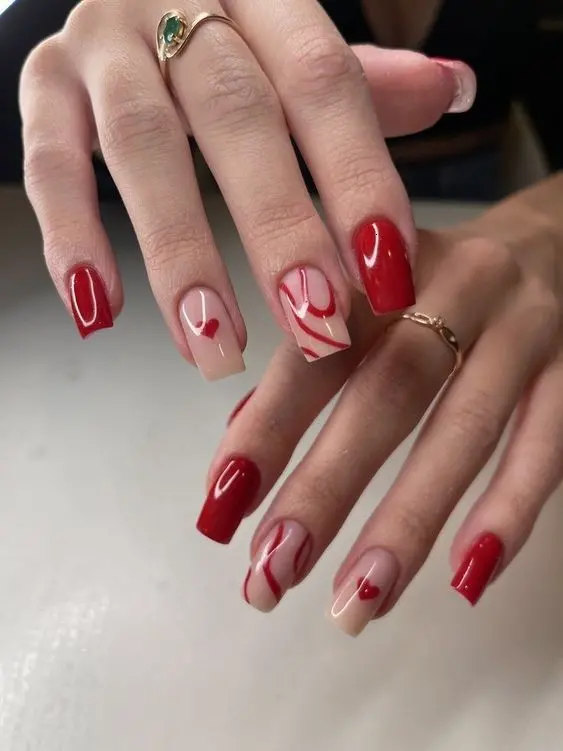 These red heart nails feature a classic square shape with glossy red polish on most nails, while the ring and middle fingers have a white base adorned with small red hearts. This style exudes elegance and romantic charm, perfect for Valentine\'s Day or special occasions.