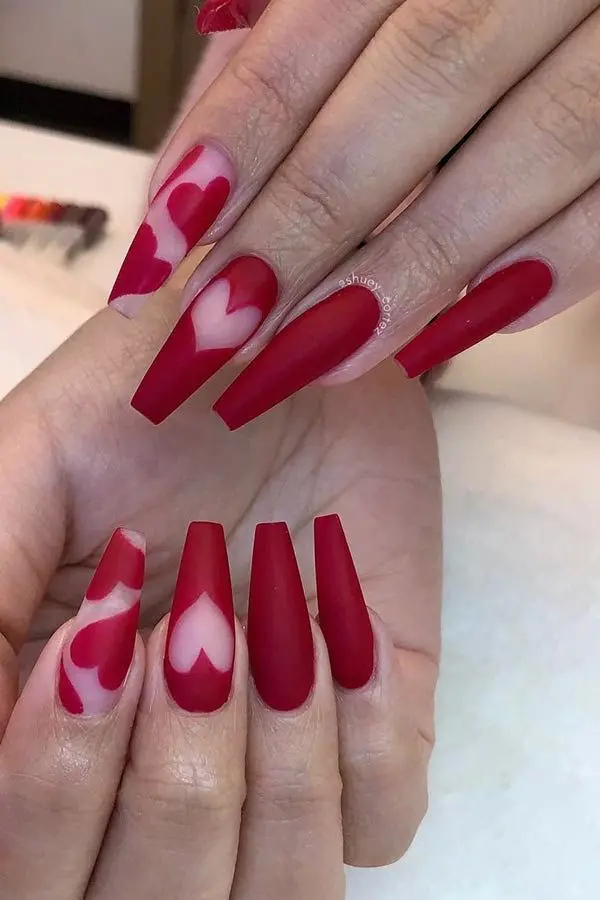 These elegant ballerina-shaped nails are painted in matte red with heart cutouts, revealing the nude base. The sophisticated design and soft matte finish create a trendy and romantic look.