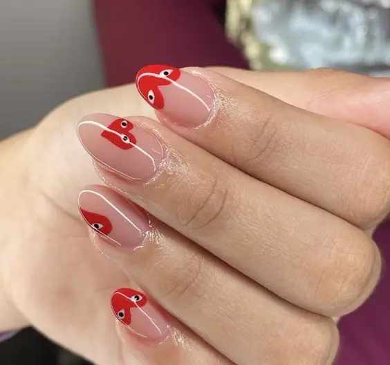 This red heart nail design is both cute and eye-catching. The natural almond-shaped nails feature red heart tips with little faces, creating a playful and unique look that is sure to turn heads.